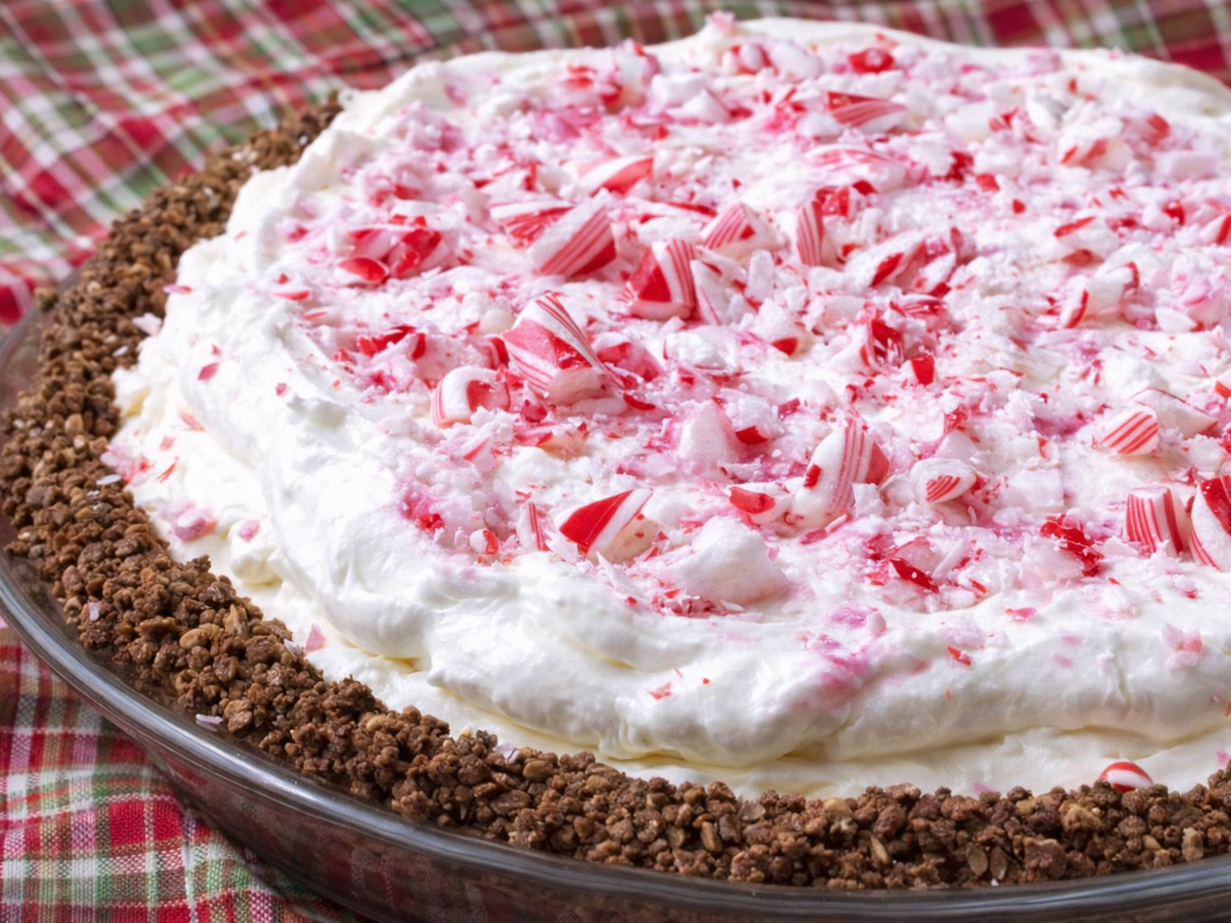 Peppermint pie topped with crushed candy and whipped cream in a glass pie dish