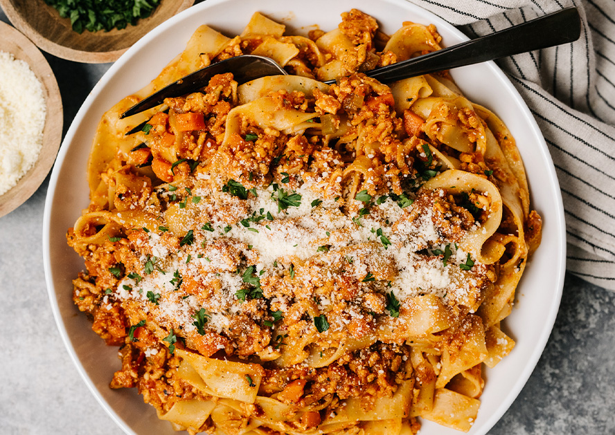 Bowl of beef taco noodle bake topped with grated cheese and herbs