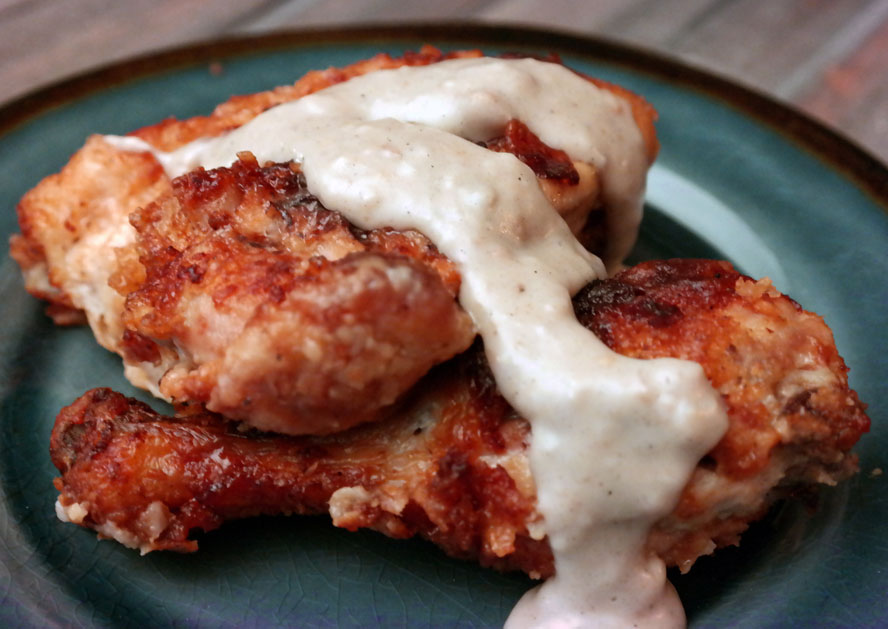 Fried chicken pieces on a plate topped with white gravy