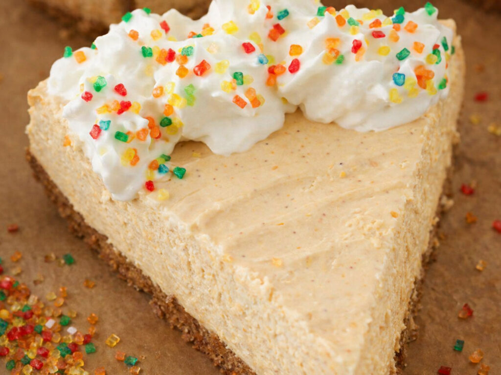 Slice of pumpkin mousse pie topped with whipped cream and colorful sprinkles