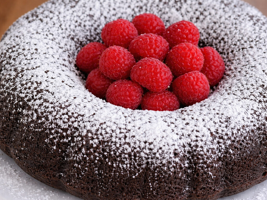Chocolate bundt cake dusted with powdered sugar and topped with raspberries