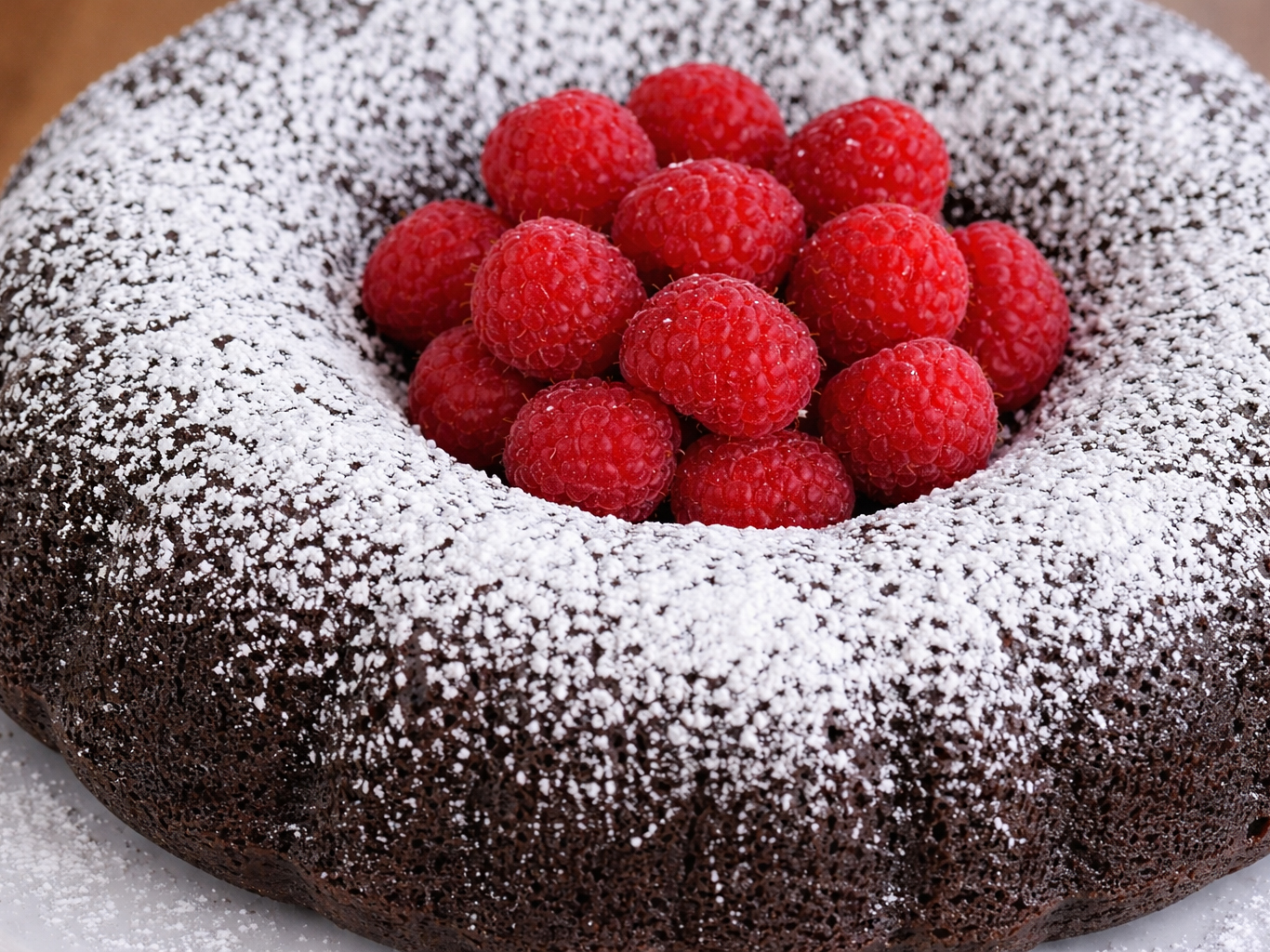 Chocolate bundt cake dusted with powdered sugar and topped with raspberries