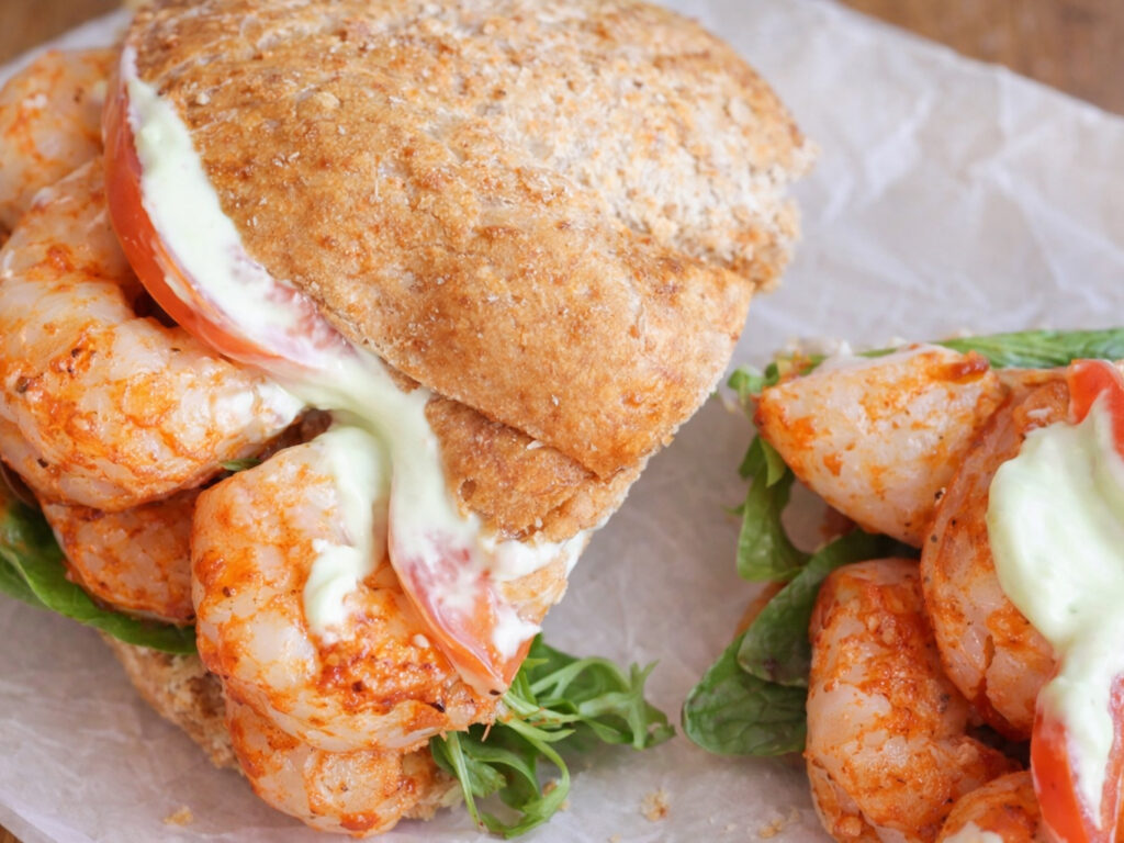 Shrimp sandwich stacks with tomato, lettuce, and melted cheese on bread