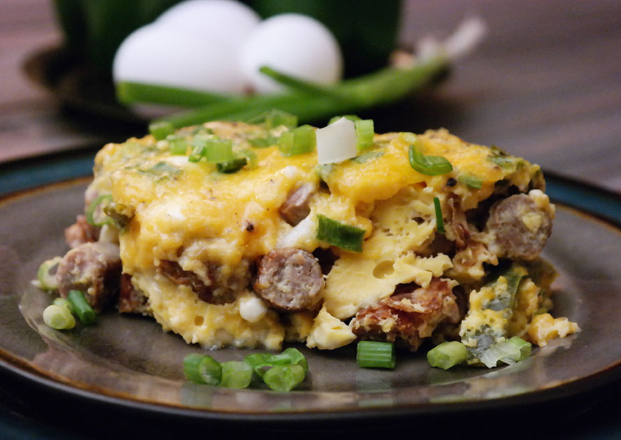Slice of egg casserole with sausage and green onions on a plate