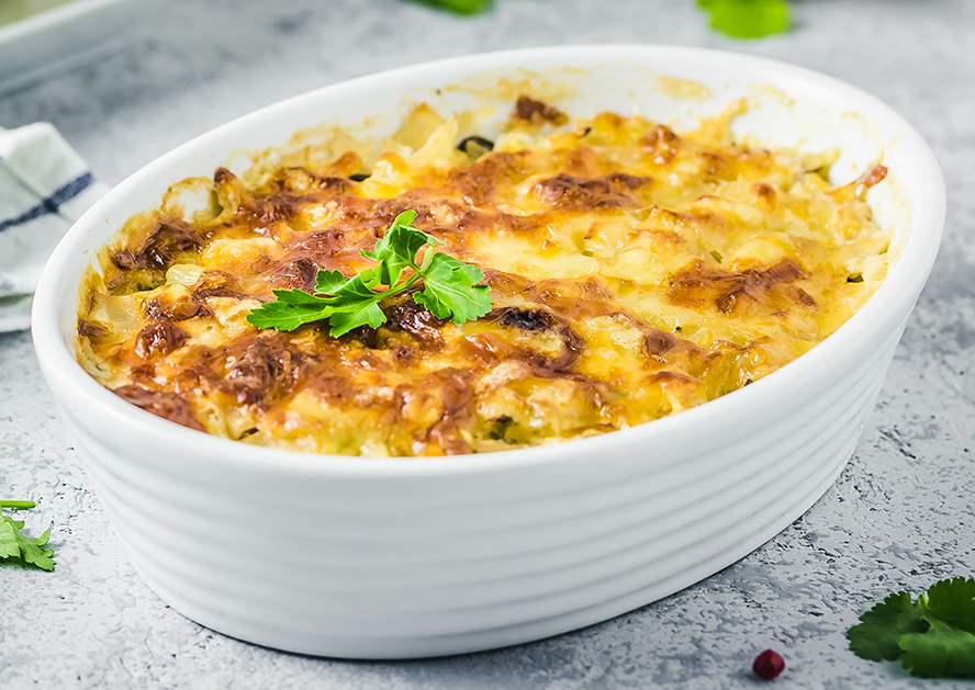 Baked potato casserole topped with melted cheese and parsley in a white oval dish