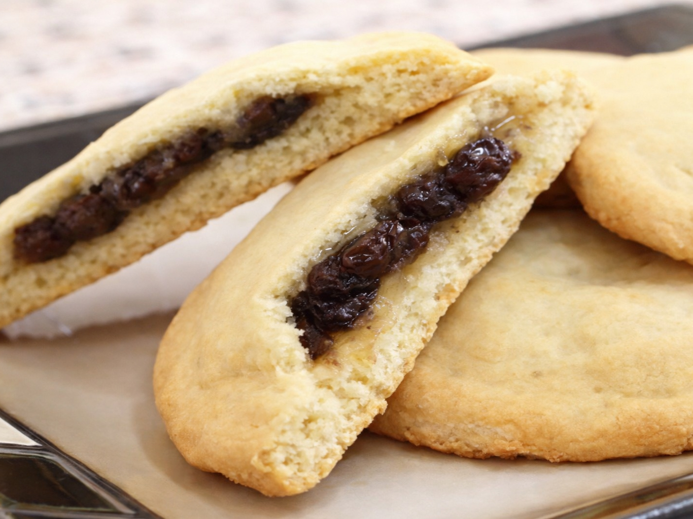 Stack of raisin-filled cookies on a plate, with one cookie split open to show the filling.