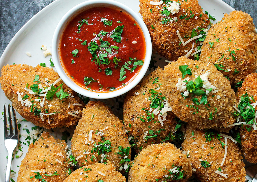 Breaded stuffed pasta shells on a plate with marinara sauce and parsley