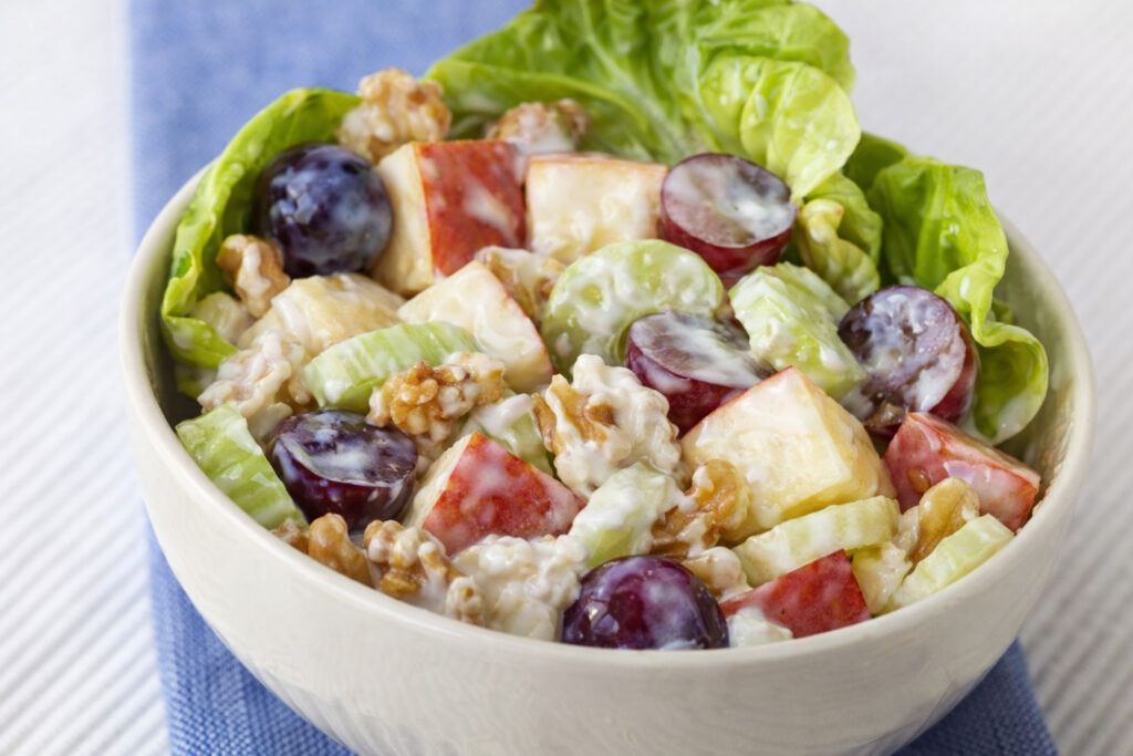Bowl of lettuce salad with apple slices, grapes, and walnuts