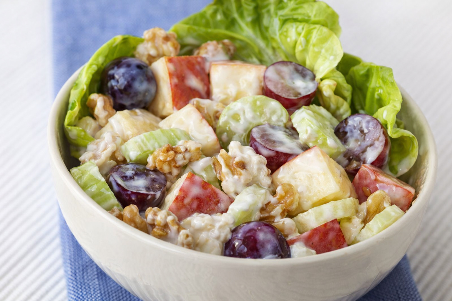 Bowl of lettuce salad with apple slices, grapes, and walnuts