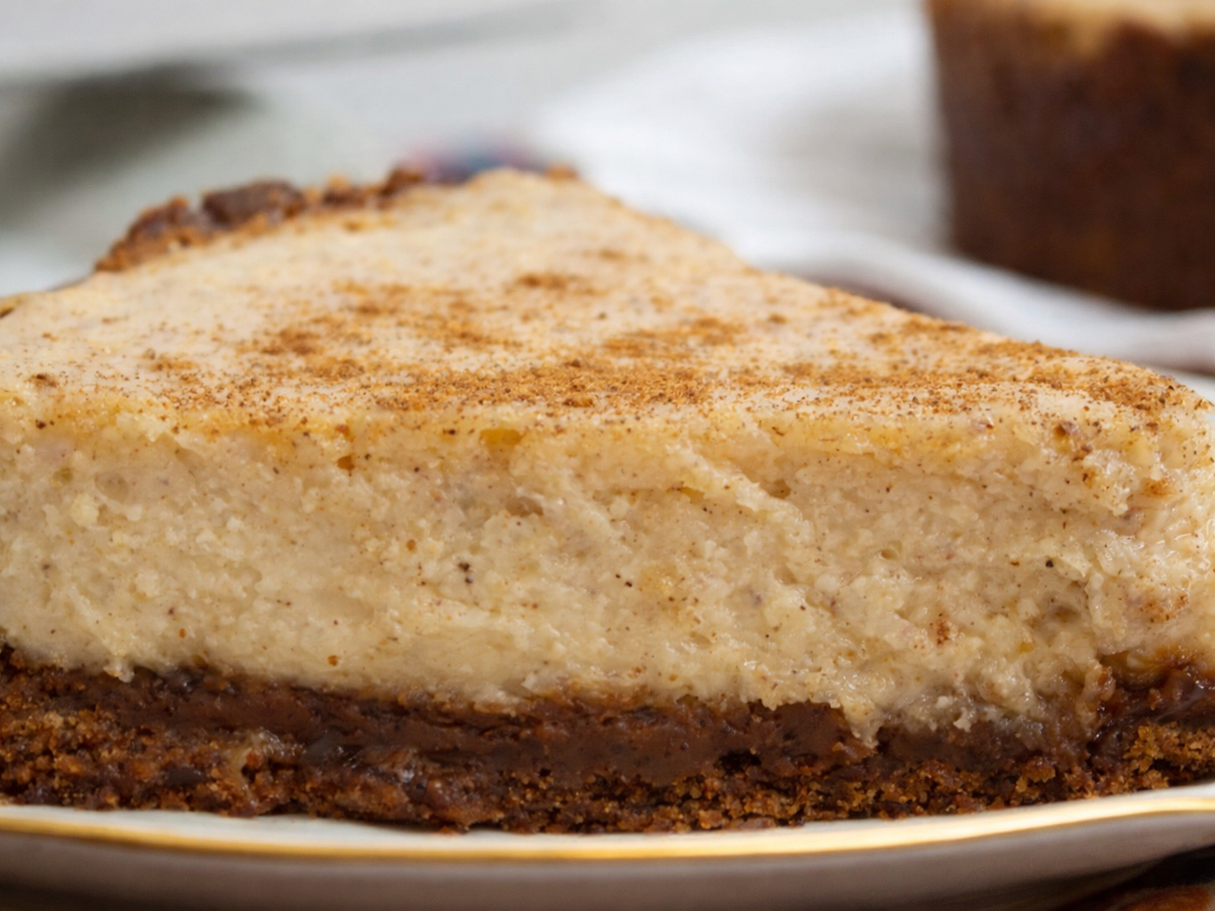 Slice of cheesecake with spiced topping and dark crust on a plate