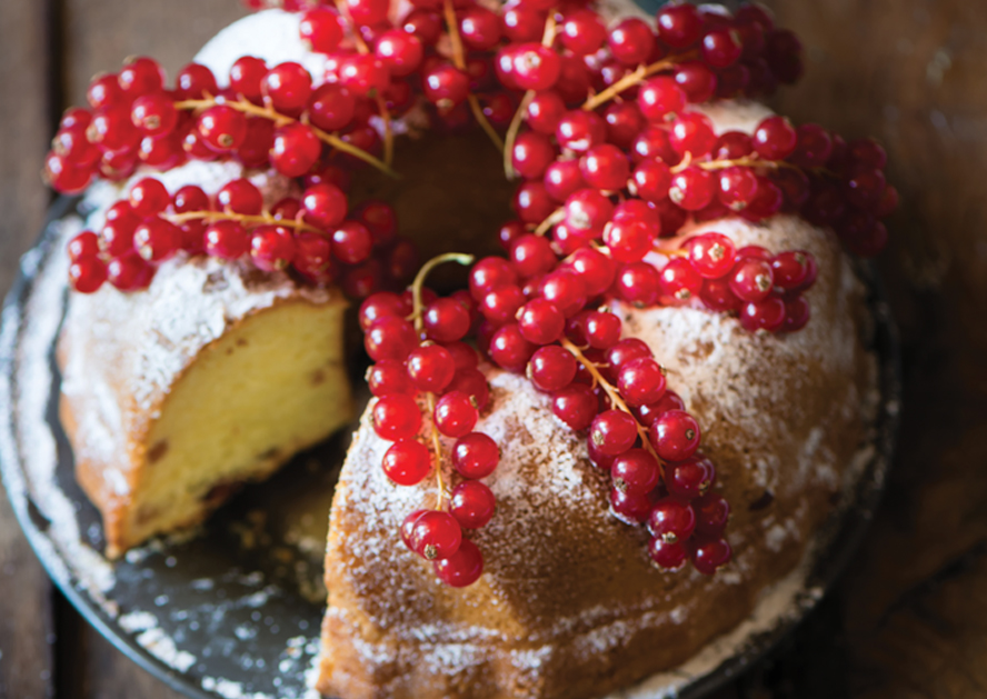 Bundt cake dusted with powdered sugar and topped with red currants