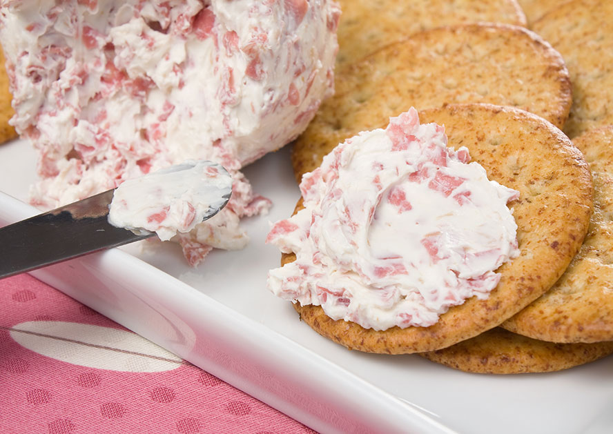 Creamy chipped beef dip served on crackers on a white tray.