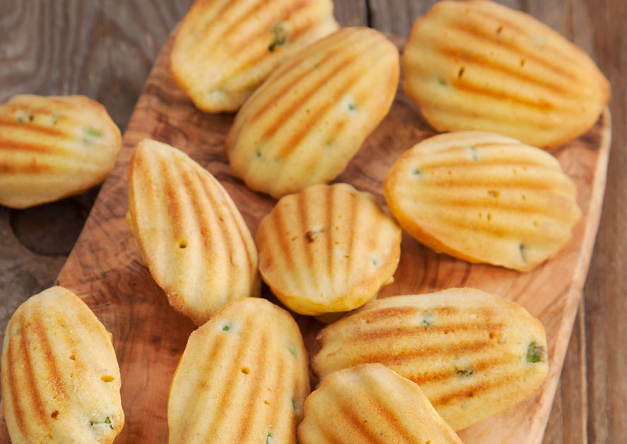 Madeleine-shaped cornbread cakes with grill marks on a wooden board