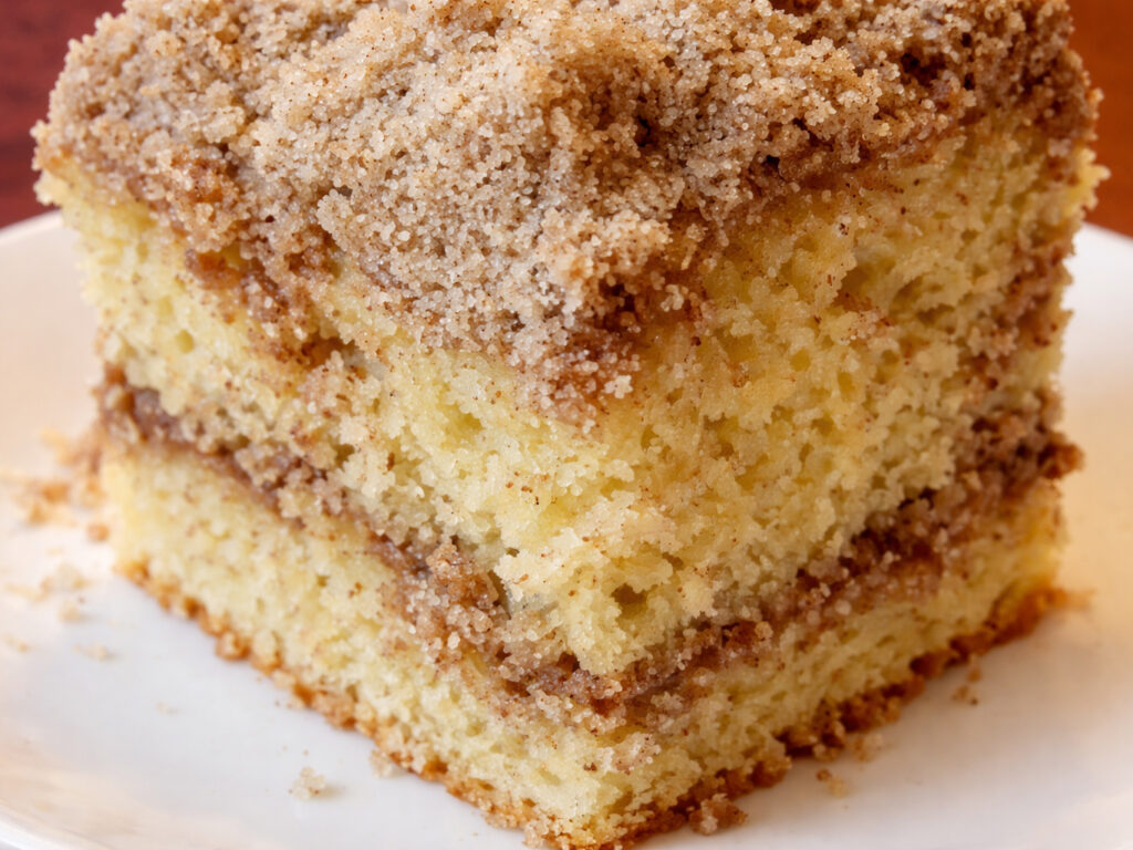 Slice of cinnamon coffee cake on a white plate