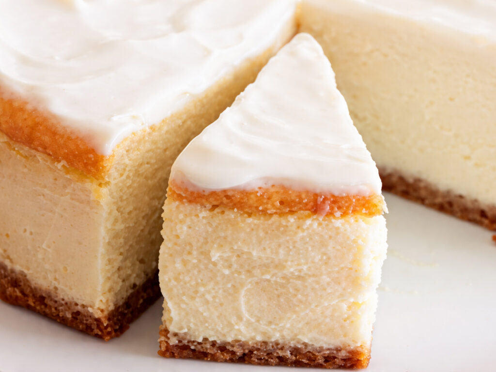 Slice of cheesecake with white frosting on a white plate