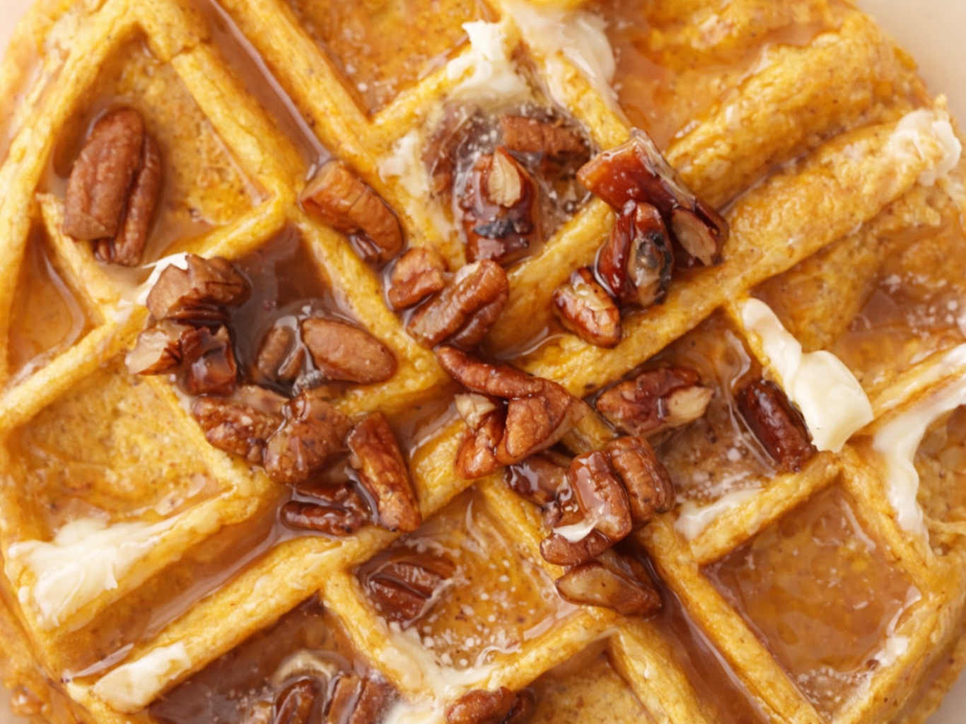Pumpkin waffles topped with pecans, syrup, and melting butter