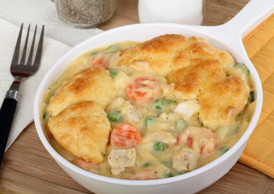 Bowl of chicken pot pie filling topped with golden biscuit pieces