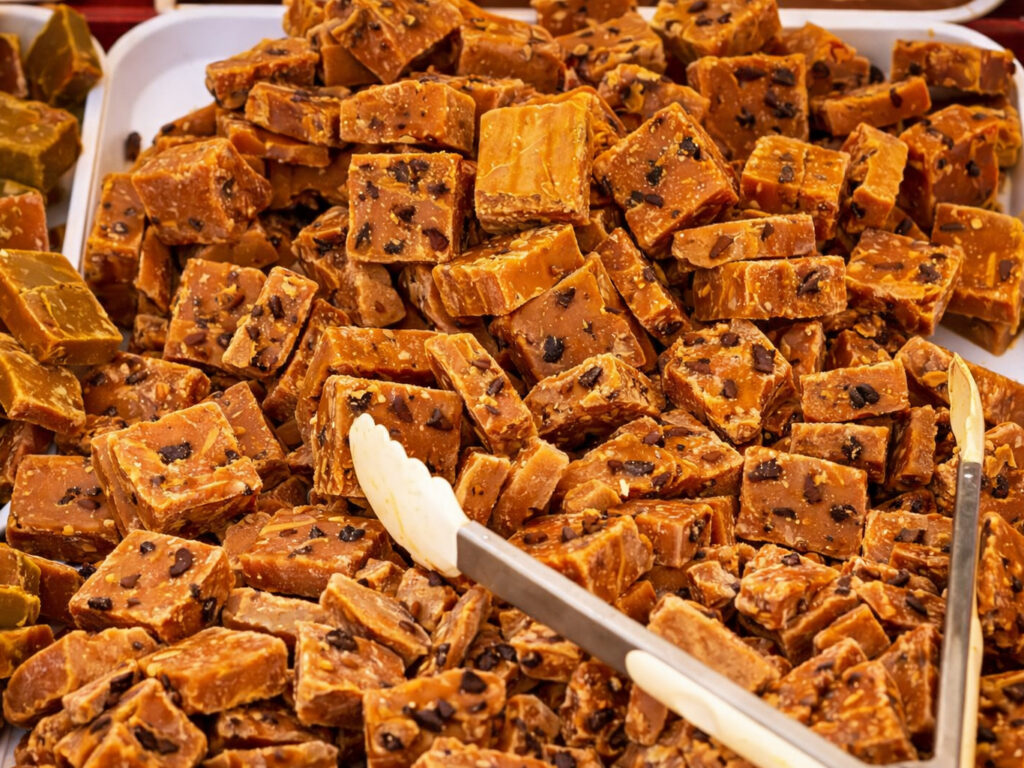 Tray filled with bite-size pieces of rum-raisin fudge, with serving tongs