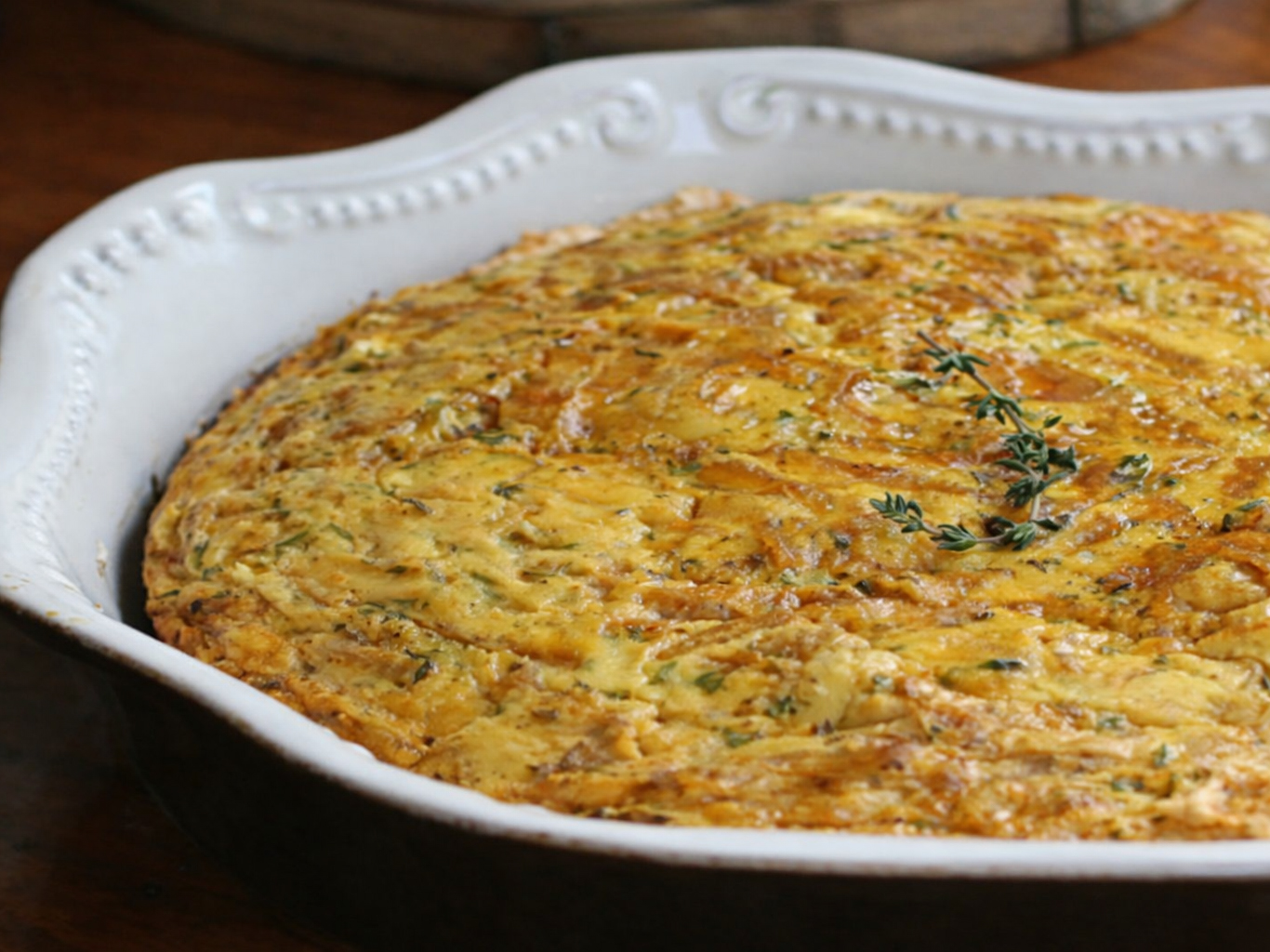 Baked cornbread in a white oval dish, topped with thyme