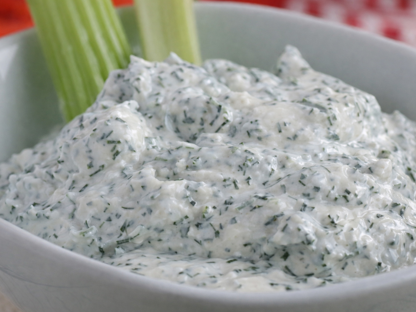 Bowl of creamy herb dip with celery sticks