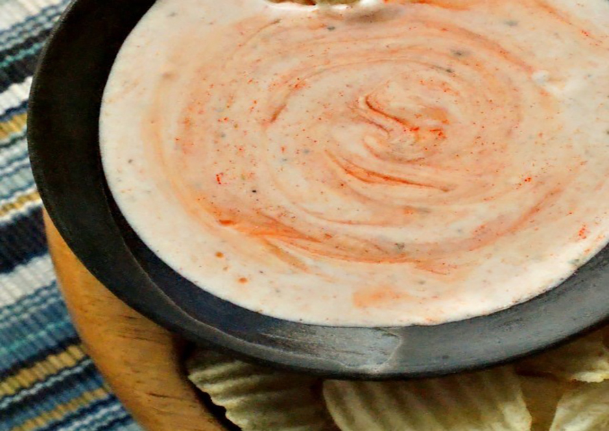 Bowl of creamy buffalo ranch dip with red swirls
