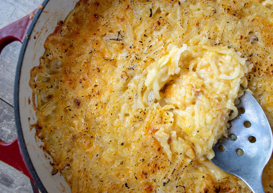 Baked hashbrown casserole being served with a slotted spoon