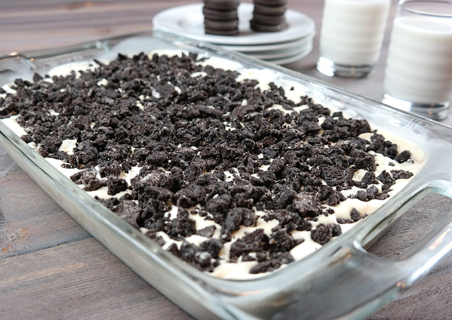 Glass baking dish filled with cookies-and-cream dessert topped with crushed chocolate cookies