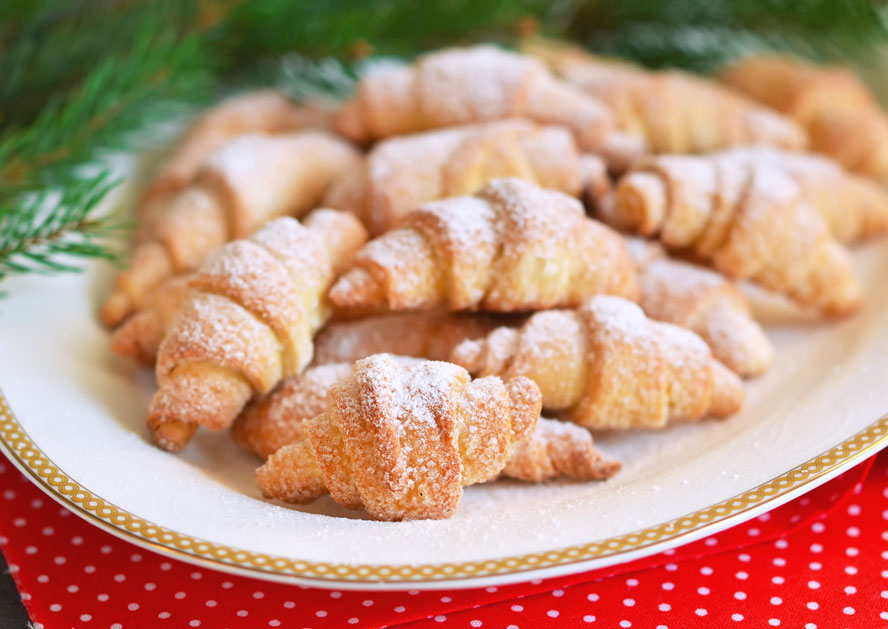 Plate of crescent-shaped pastries dusted with powdered sugar