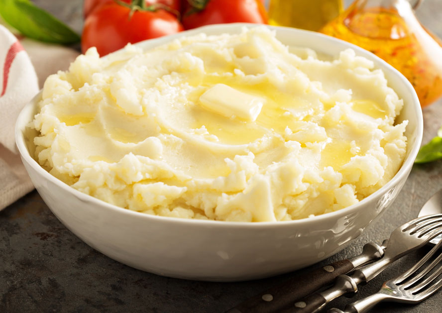 Bowl of mashed potatoes topped with melted butter