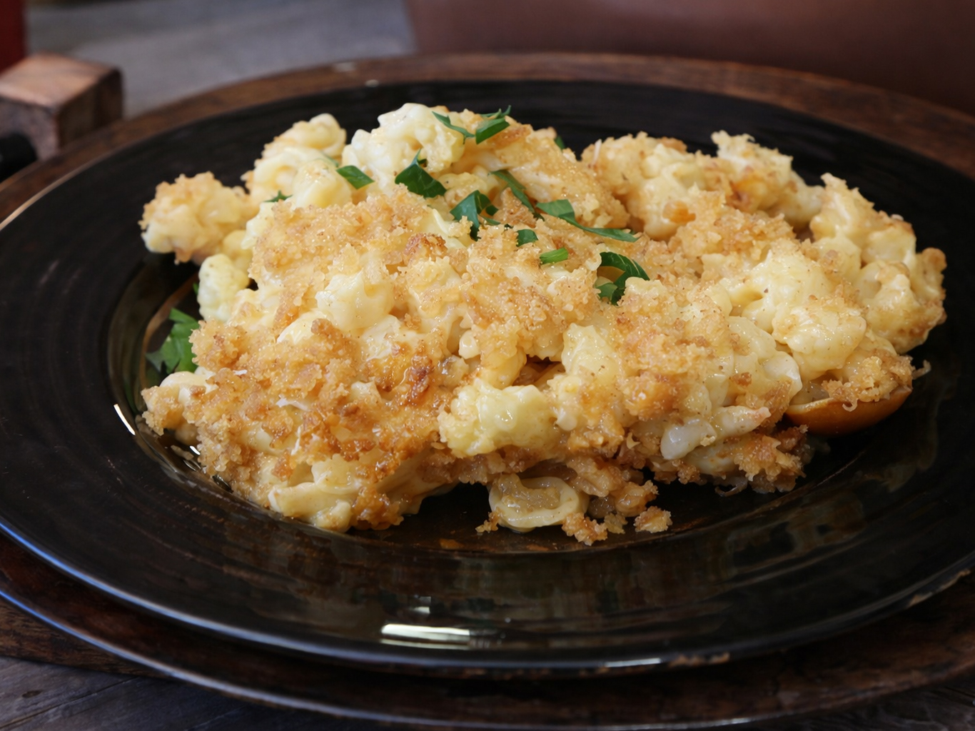 Baked macaroni and cheese with a golden breadcrumb topping on a dark plate