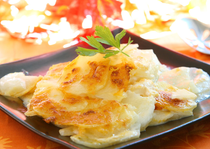 Baked scalloped potatoes topped with parsley on a black plate