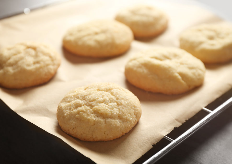 Six golden drop cookies on parchment paper on a baking sheet