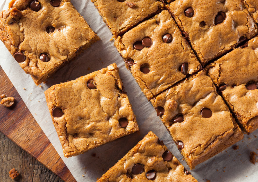 Chocolate chip blondie bars cut into squares on parchment paper