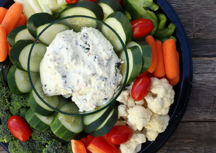 Vegetable platter with dip, cucumber slices, carrots, broccoli, cauliflower, and cherry tomatoes