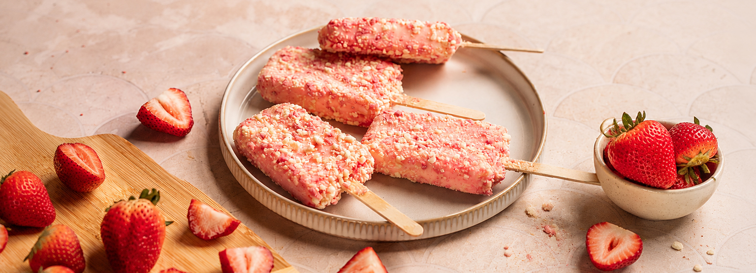 Prairie Farms Strawberry Shortcake bars coated in crunchy strawberry and vanilla crumbs arranged on a plate with fresh strawberries scattered around