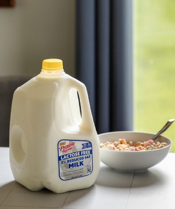 Prairie Farms Lactose Free 2% Reduced Fat Milk gallon beside a bowl of cereal on a kitchen table