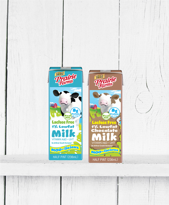 Prairie Farms Lactose Free 1% Lowfat Milk and Lactose Free 1% Lowfat Chocolate Milk shelf-stable cartons displayed side by side on a white wooden shelf