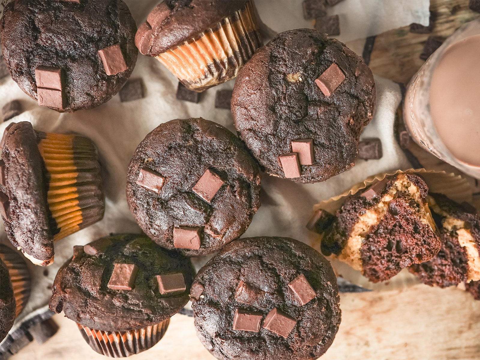 Chocolate peanut butter muffins topped with chocolate chunks, with one muffin cut open to reveal a creamy peanut butter filling.