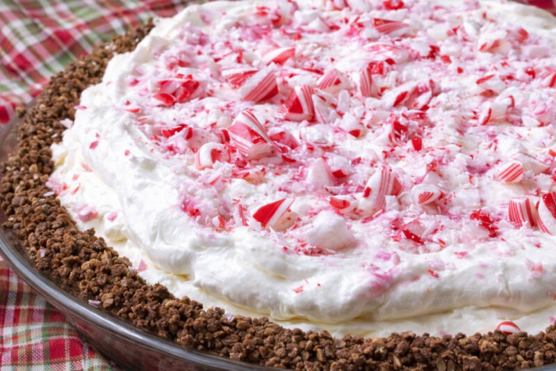 Peppermint pie topped with crushed candy and whipped cream in a glass pie dish