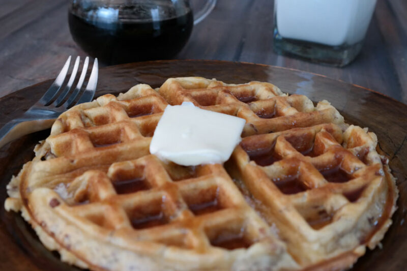 Waffle topped with a pat of butter on a brown plate