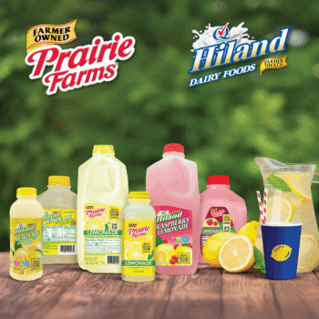 Assorted Prairie Farms and Hiland lemonade products, including classic and raspberry lemonade in various bottle sizes, displayed on a wooden surface with fresh lemons and a pitcher of lemonade, with both brand logos shown above against a green background