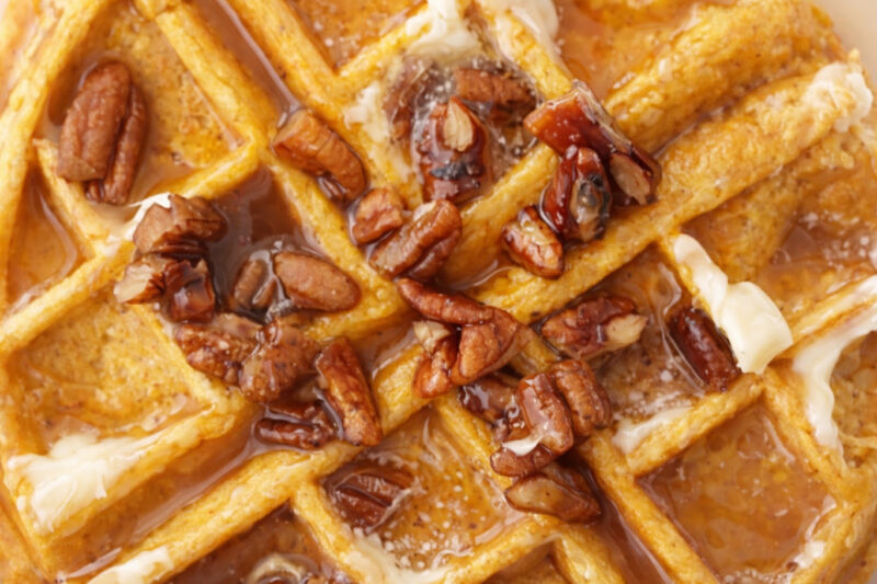 Pumpkin waffles topped with pecans, syrup, and melting butter