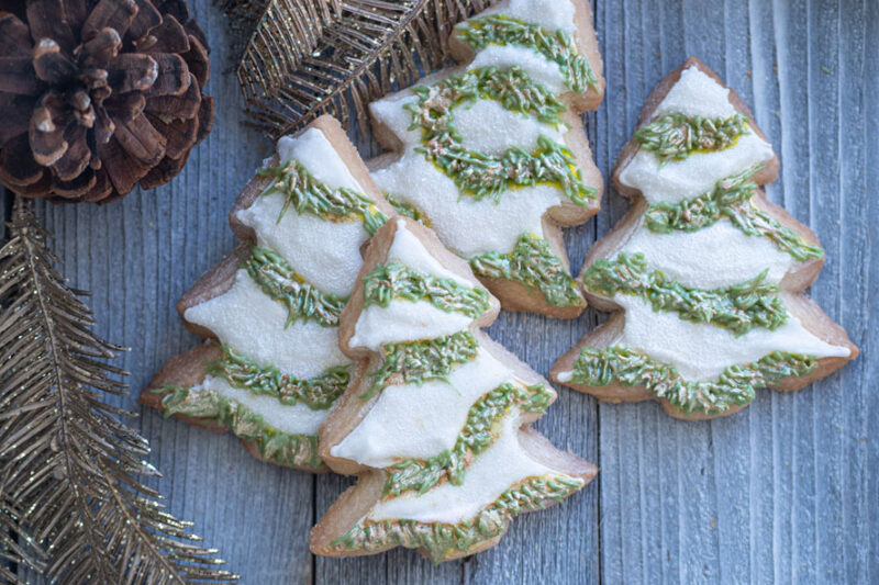 Christmas tree-shaped frosted cookies with green icing on a wooden surface