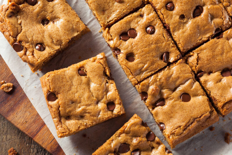 Chocolate chip blondie bars cut into squares on parchment paper