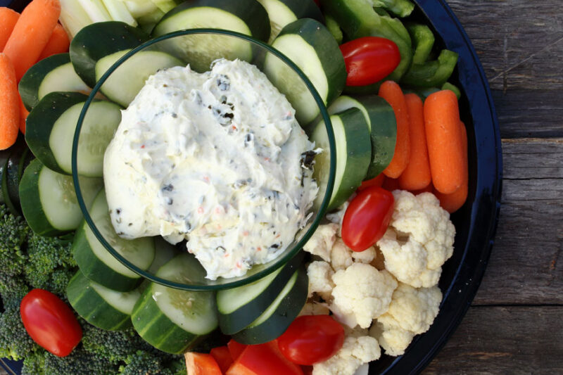 Vegetable platter with dip, cucumber slices, carrots, broccoli, cauliflower, and cherry tomatoes
